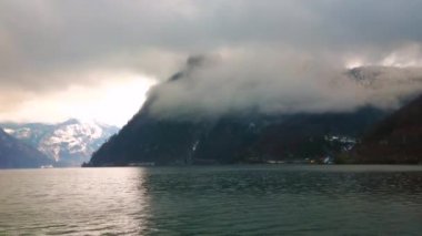 Traunsee gölü, Traunkirchen, Salzkammergut, Avusturya'da Alp zirveleri etrafında toplanarak, düşük yağmurlu bulutlarda delikten parlak gün batımını izleyin
