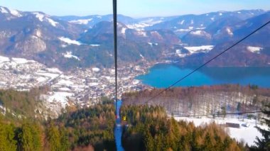 Vintage Zwolferhorn teleferiğine binin ve Salzkammergut'un manzarasını, Wolfgangsee dağ gölünü, karlı yamaçtayem kozalaklı ormanları gözlemleyin, St Gilden, Avusturya.