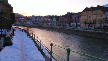 Renkli geleneksel şehir evleri ve parlak gökyüzü manzaralı Traun nehri karlı gezinti boyunca yürürken gün batımının keyfini çıkarın, dalgalı sulara yansıyan, Bad Ischl, Salzkammergut, Avusturya