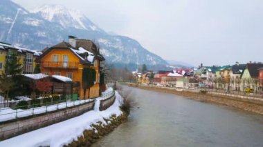 Arka planda Katrin Dağı'nın sisli bir yamacı ile Traun nehri kar bağlı kıyısında eski villalar, Bad Ischl, Salzkammergut, Avusturya.
