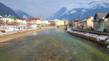 Tarihi konut, Parish kilise uzun çan kulesi, Traun nehri ve karlı Alpler, Bad Ischl, Salzkammergut, Avusturya taş kıyıları ile nehir kenarı şehir manzarası