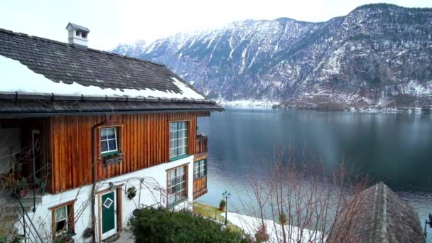 The view on Hallstattersee lake and snowy Dachstein Alps from the slope of Salzberg mountain, covered with old houses of Hallstatt, Salzkammergut, Austria — Stock Footage View Hallstattersee Lake Snowy Dachstein Alps Slope Salzberg Mountain Covered Stock Footage