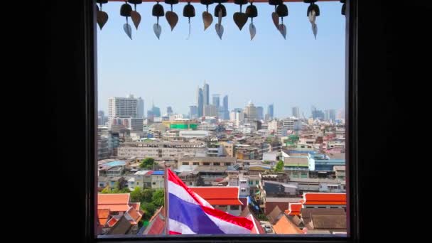 曼谷天际线与挥舞的泰国国旗和佛教祈祷钟 悬挂在位于泰国金山山顶的萨凯寺的窗户上 — 图库视频影像