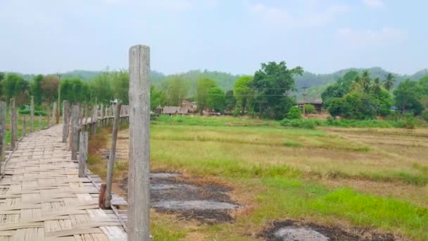 古いストンペ竹橋のパノラマをお楽しみください 高い木製のポールを持つ長い狭く湾曲した構造で タイのメーホンソン郊外の農地と水田に沿って伸びています — ストック動画