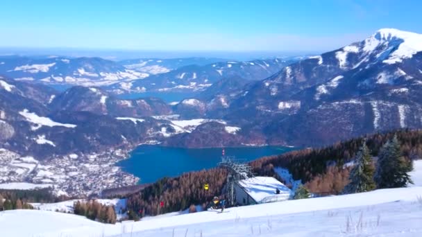 ヴォルフガング湖の谷に積もった雪のズヴォルファーホルン山の頂上からの眺め ケーブルカーの色付きゴンドラ ザルツカンマーグート セントギルデン オーストリアのアルプスの風景 — ストック動画