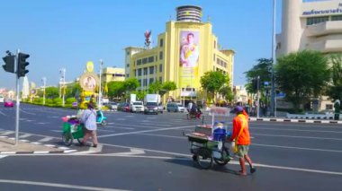 Bangkok, Tayland - 24 Nisan 2019: Sokak gıda satıcıları modern binalar ve Demokrasi Anıtı manzaralı geniş Ratchadamnoen Caddesi üzerinden arabaları ile yürümek, Bangkok Nisan'da 24