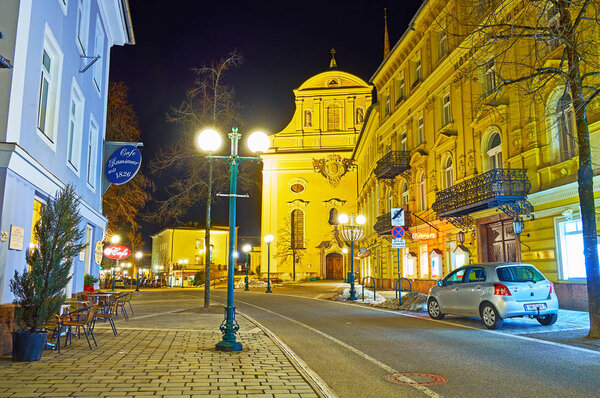 BAD ISCHL, AUSTRIA - FEBRUARY 20, 2019: Evening Franz Joseph Strasse with a view on illuminated St Nicholas Parish Church and classical buildings, on February 20 in Bad Ischl