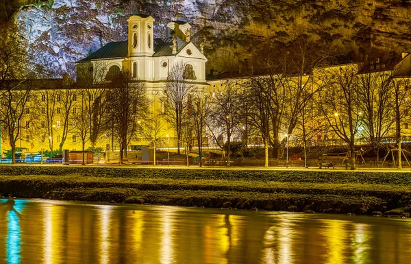 De verlichte kerk aan de Salzach oever van de rivier, Salzburg, Oostenrijk — Stockfoto