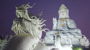 Guan Yin dev beyaz heykeli (Tanrıça Mercy), ön planda ejderha kafası (Naga yılan) bir görünüm ile tepenin üzerinde büyük lotus üzerinde oturan, Wat Huai Pla Kang, Chiang Rai, Tayland