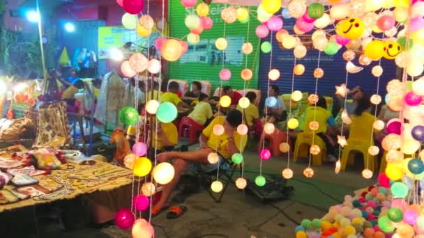 チェンマイ 2019年5月4日 チェンマイで5月4日に土曜日の夜の市場 ウライウォーキングストリートで点灯した花輪の後ろに見えるオープンエアタイマッサージサロン チェンマイで5月4日 — ストック動画