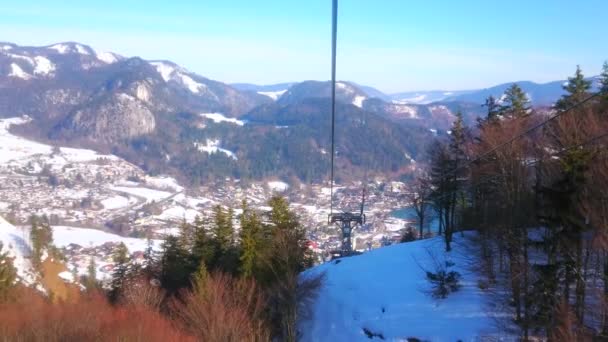スキーピストと緑豊かなスプルースの森で覆われた雪の山の斜面の上に伸びるズウォルファーホルンケーブルウェイのゴンドラから冬の自然を観察 セントギルゲン ザルツカンマーグート オーストリア — ストック動画