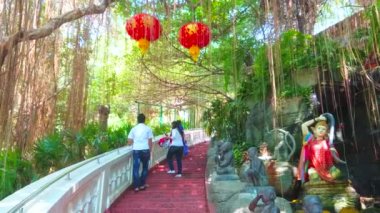 Bangkok, Tayland - 24 Nisan 2019: Banyan ağaçları, palmiyeler, şelale ve Toprak Tanrıçası heykeli ile Golden Mount (Wat Saket) Tapınağı'nın yamacında gölgeli tropikal bahçe, 24 Nisan'da Bangkok