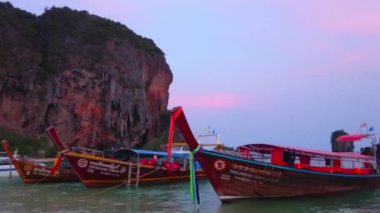 Ao Nang, Tayland - 26 Nisan 2019: Renkli kurdeleler ve çelenkler ile ahşap uzun kuyruklu tekneler Railay (Rai Leh) Yarımadası'nın alacakaranlık Phra Nang plajdemirli, Nisan'da 26 Ao Nang 