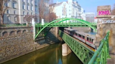 Viyana, Avusturya - 18 Şubat 2019: Trenler Wien Nehri üzerindeki Zollamtsbrucke köprüsünden yaya kemerli Zollamtssteg köprüsünün altından geçiyor, 18 Şubat'ta Viyana'da.