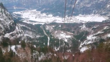Krippenstein dağının dik yamacından aşağı yamaçtan aşağı yakılan hava asansörü, Obertraun vadisine, Dachstein masifinin kayalık Alplerine ve kış ormanlarına, Salzkammergut, Avusturya'ya bakmaktadır.