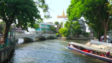 BANGKOK, THAILAND - 24 Nisan 2019: Uzun feribot, 24 Nisan 'da Bangkok' taki Golden Mount Tapınağı 'ndan geçen Maha Nak Khlong' un (kanal) dar alanında karmaşık manevralar yapar.