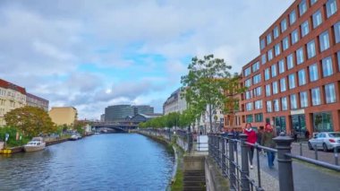 Berlin, Almanya - 3 Ekim 2019: İnsanlar 3 Ekim 'de Berlin' de Spree nehri boyunca yüzen tekneler ve Friedrichstrasse demiryolu köprüsü manzaralı bir şekilde yürüyorlar.