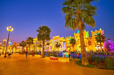 DUBAI, BAE - 5 Mart 2020 'de, farklı ülkelerin aydınlık ticaret pavyonları önünde, Global Village Dubai kanalı boyunca uzanan palmiye yolu, 5 Mart' ta Dubai 'de