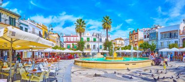 SANLUCAR, SPAIN - SEPTEMBER 22, 2019: Tarihi Plaza del Cabildo Meydanı, 22 Eylül 'de Sanlucar' da serinletici fıskiyeler, mevcut kasaba evleri ve açık hava restoranları ile popüler şehir merkezidir.