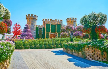 DUBAI, BAE - 5 Mart 2020: Çevresinde bereketli çalılar, ayçiçekleri ve petunya bulunan manzaralı küçük kale kopyası, Miracle Garden, 5 Mart 'ta Dubai' de