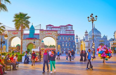 DUBAI, BAE - 5 Mart 2020: Dubai Global Village Dubai 'de 5 Mart' ta Dubai Kale duvarı, kemerler ve Konya yeşil kulesinin taklidiyle süslenmiş küçük Tac Mahal ve Türkiye pavyonu ile kalabalık sokak