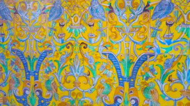 SEVILLE, SPAIN - 1 Ekim 2019: Seville 'deki Alcazar Sarayı' nda, tipik bir çiçek süsü ve mitolojik yaratıkların maskeleriyle renkli Endülüs tarzı duvar panoraması