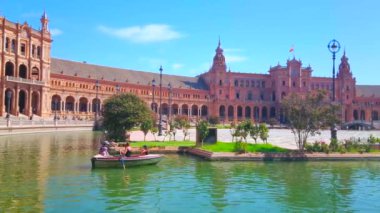 SEVILLE, SPAIN - 1 Ekim 2019: Turist tekneleri, 1 Ekim 'de Seville' de Endülüs tarzında büyük bir kompleksle süslenmiş Plaza de Espana meydanındaki dar kanal boyunca yüzüyor.