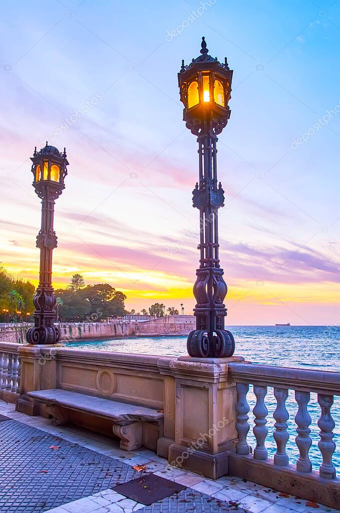 The oceanside promenade along the San Carlos ramparts is decorated with scenic vintage cast iron streetlights, Cadiz, Spain