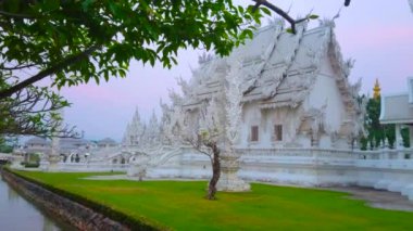 Beyaz Tapınak (Wat Rongkhun) sulu çimenler ve bahçenin yemyeşil ağaçları ile çevrilidir.
