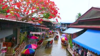 DAMNOEN SADUAK, THAILAND - 13 Mayıs 2019 Damnoen Saduak yüzen pazarının renkli şemsiyeleri ve botları, çatıları üzerinde dar khlong ve çiçek açan alev ağacıyla 13 Mayıs 'ta Damnoen Saduak' ta