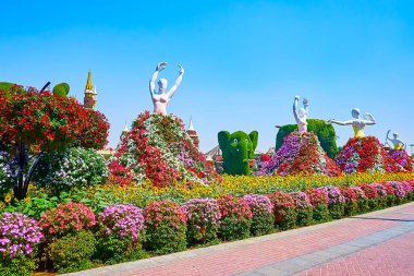 DUBAI, BAE - 5 Mart 2020: Mucize Bahçesi manzaralı ara sokakta yürümek, muhteşem petunyalar ve ayçiçekleriyle süslenmiş ve 5 Mart 'ta Dubai' de dans eden balerin figürleriyle süslenmiş