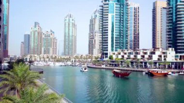 DUBAI, BAE - 2 Mart 2020 'de Dubai limanı boyunca Marina gezinti güvertesi ve modern gökdelenlerle dolu eski moda ahşap dhow teknesi 2 Mart' ta Dubai 'de yüzüyor.