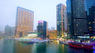 DUBAI, BAE - 2 Mart 2020: Alacakaranlıkta Dubai Marina 'nın aydınlık panoraması; 2 Mart' ta Dubai limanında liman kenti Dubai Marina Marina Hotel 'in gelecekteki binası demirli yatların arkasında görüldü.