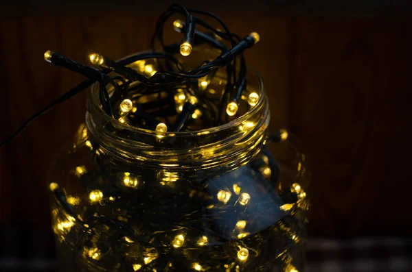 Noel ışıkları. Dekoratif ışıklar. Sıcak beyaz led ışıkları. Karanlıkta damalı bir masa örtüsü üzerinde bir kavanoza Noel Işık dekorasyon.