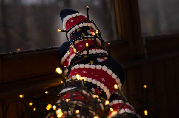 Sıcak beyaz ışıklar ve ayak Noel çorap yol açtı. Geç akşam evde kız rahatlatıcı. Kış tatil Noel ve yeni yıl kavramı. Pencere tarafından yün çorap ayak.