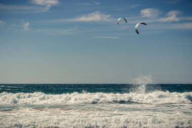 Guincho plaj denizi, sörfçülerin uçurtma uçurduğu arka planda mavi gökyüzü, Cascais, Portekiz