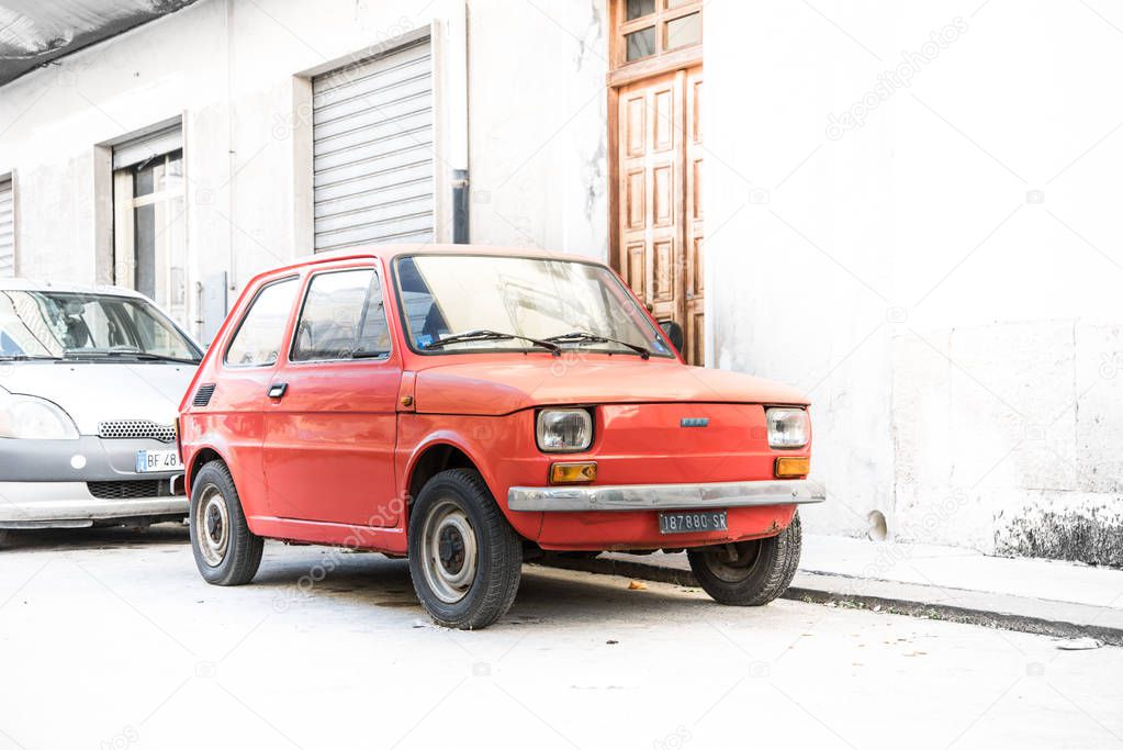 Ortigia, Syracuse, Italy / December 2018: Red old Fiat 126 Bambino parked on old street