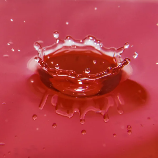 Salpicadura de agua aislada sobre fondo rojo —  Fotos de Stock