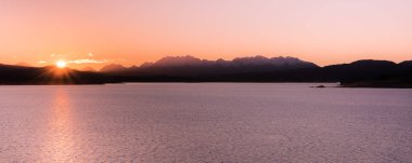 Dağlar ve backgr mor gökyüzü ile okyanusta gündoğumu