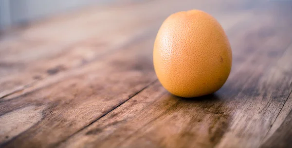 Стиглий апельсин ізольований на сільському старовинному дерев'яному столі — стокове фото