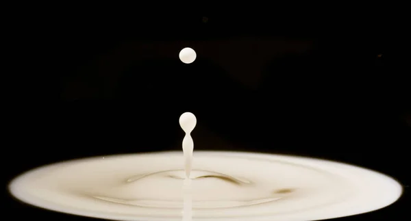 Gota de leche: gotita de leche que cae sobre el líquido blanco y crea —  Fotos de Stock