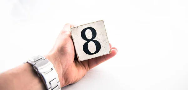 Una mano sosteniendo el dígito número 8 (ocho) sobre fondo blanco — Foto de Stock