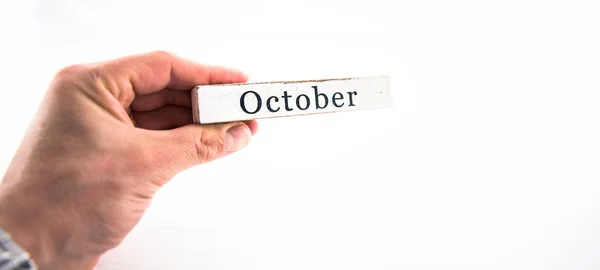 Outubro - Um bloco de mês de calendário de mão segurando no backgroun branco — Fotografia de Stock
