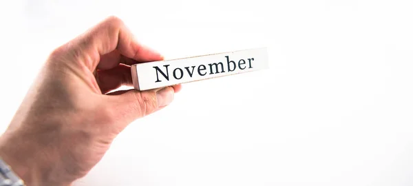 Novembro - Um bloco de mês de calendário de mão segurando no backgrou branco — Fotografia de Stock