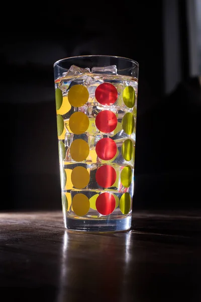 Hohes farbenfrohes Glas gefüllt mit eisgekühlter Limonade isoliert auf dunklem — Stockfoto