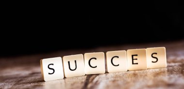 Karanlık ahşap arka plan üzerinde fayans yapılmış Succes kelime 