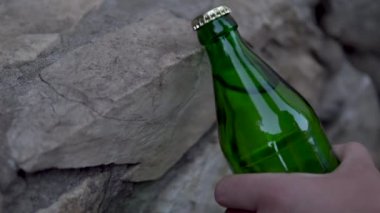 Bir adam kaldırıma vuran gazlı içecek şişesini açmaz. Metal kapaklı cam şişe