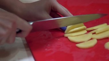 Bir kadın kırmızı bir tahtaya patates leşdirdi.