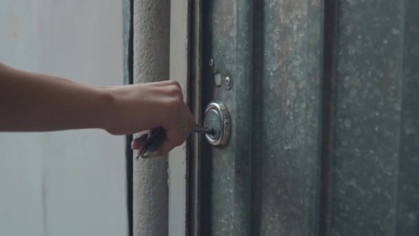 La chica abre la cerradura de la puerta con una llave grande y entra por la puerta — Vídeos de Stock