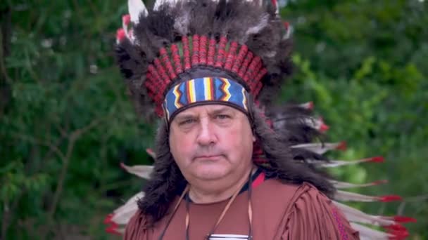 Yaşlı Amerikan yerlileri elini kaldırıyor. Ormanın arka planında duruyor. — Stok video